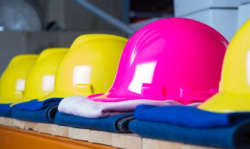 A row of hard hats on folded workwear, ready for an after builders clean